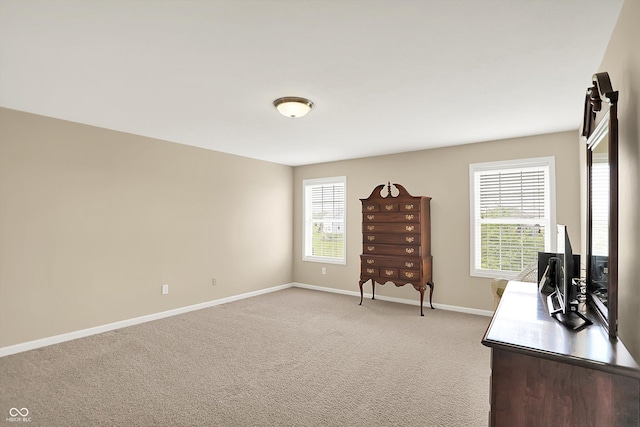 office area featuring baseboards and light carpet