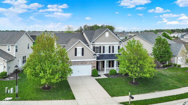 view of front of house with stone siding, a porch, driveway, a residential view, and a standing seam roof