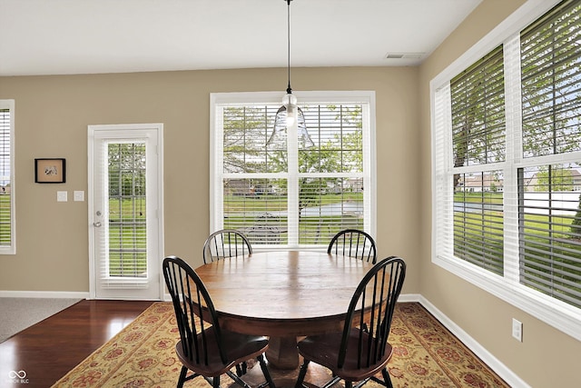 dining area with plenty of natural light, baseboards, and dark wood-style flooring