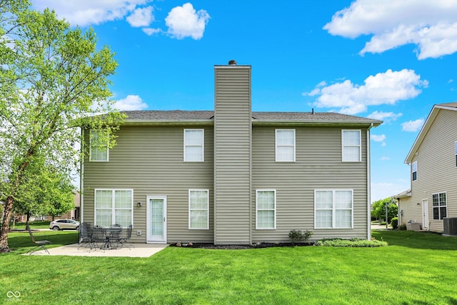 back of house featuring a patio area, a lawn, a chimney, and central AC