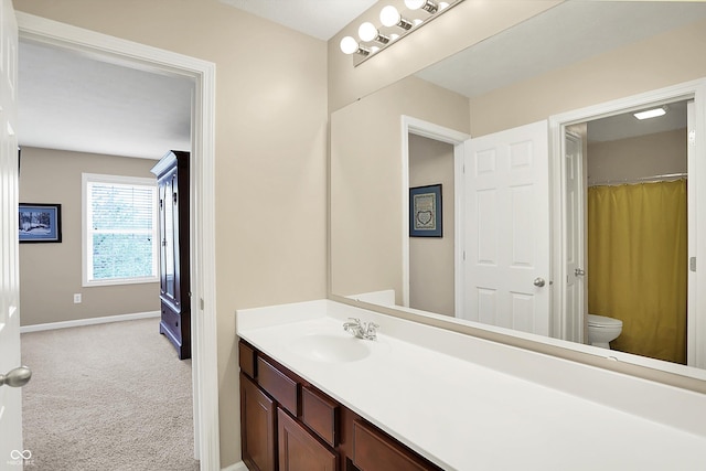 bathroom featuring toilet, baseboards, and vanity