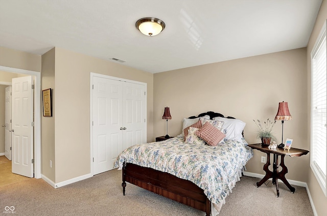 bedroom with light colored carpet, baseboards, and a closet