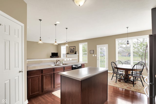 kitchen featuring dishwasher, freestanding refrigerator, a sink, dark wood-type flooring, and light countertops