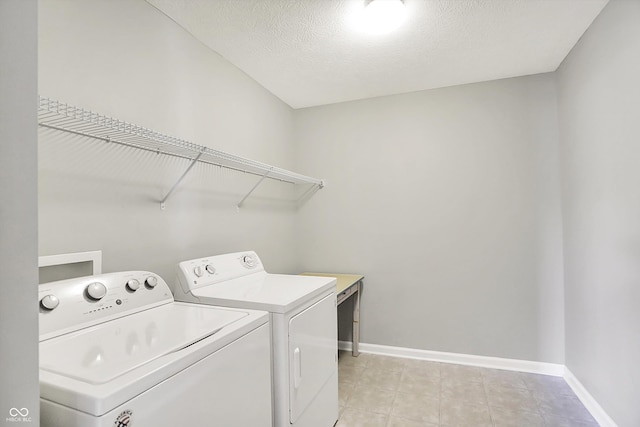 laundry room featuring washer and dryer, baseboards, light tile patterned flooring, and a textured ceiling
