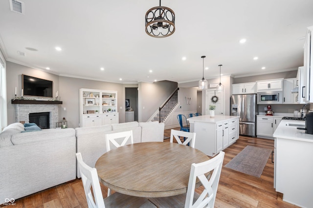 16270 Northwind Ct, Westfield, IN 46074 - dining room featuring ornamental molding, recessed lighting, stairway, a stone fireplace, and light wood finished floors