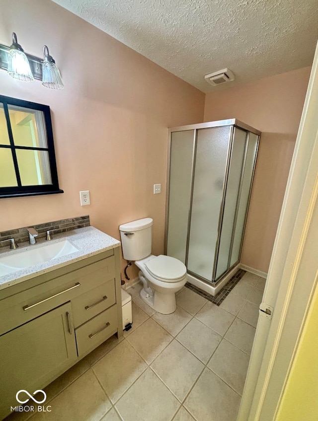 full bath featuring a stall shower, tile patterned floors, toilet, a textured ceiling, and vanity