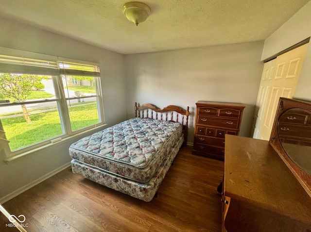 bedroom featuring dark wood finished floors, baseboards, and a textured ceiling