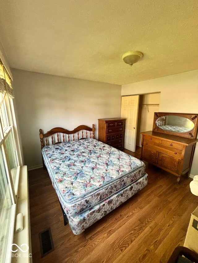 bedroom with wood finished floors, a closet, baseboards, and a textured ceiling