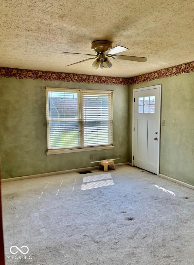 carpeted entryway with ceiling fan, a textured ceiling, and baseboards