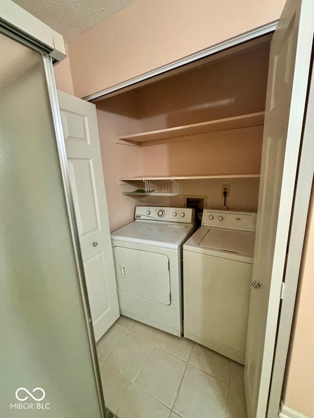 clothes washing area featuring washer and dryer and light tile patterned flooring