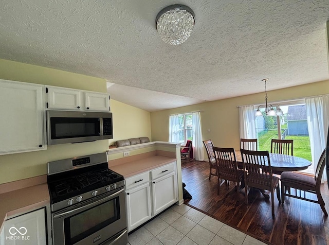kitchen featuring appliances with stainless steel finishes, a chandelier, white cabinets, light countertops, and a textured ceiling