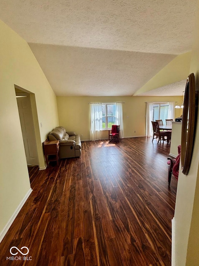 living area with vaulted ceiling, a textured ceiling, wood finished floors, and baseboards