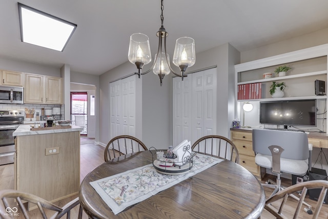 dining area featuring light wood finished floors, a chandelier, an office area, and baseboards