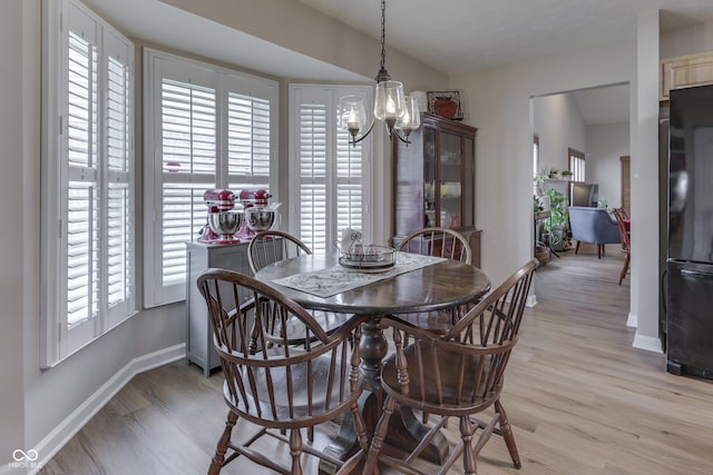 dining space with light wood-type flooring, a chandelier, and baseboards