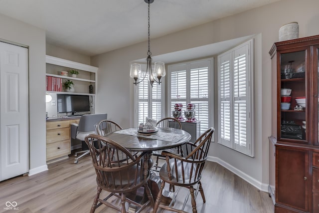 dining space with plenty of natural light, light wood-type flooring, a chandelier, and baseboards