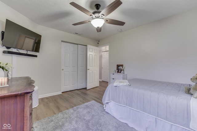 bedroom with wood finished floors, baseboards, a closet, and a ceiling fan