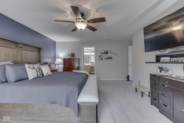 bedroom featuring light colored carpet, ensuite bath, baseboards, and ceiling fan