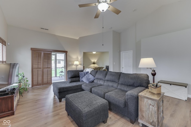living area featuring a ceiling fan, light wood-type flooring, a high ceiling, and baseboards