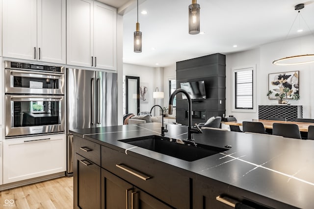 2036 Central Ave, Indianapolis, IN 46202 - kitchen featuring a sink, stainless steel appliances, light wood-type flooring, dark countertops, and pendant lighting
