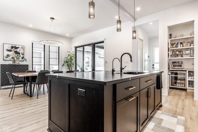 2036 Central Ave, Indianapolis, IN 46202 - kitchen with wine cooler, a sink, light wood-style floors, an island with sink, and dark countertops