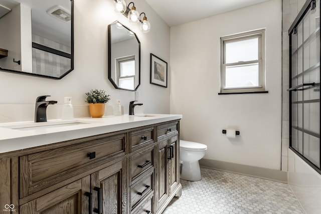 full bathroom with toilet, double vanity, baseboards, and tile patterned floors