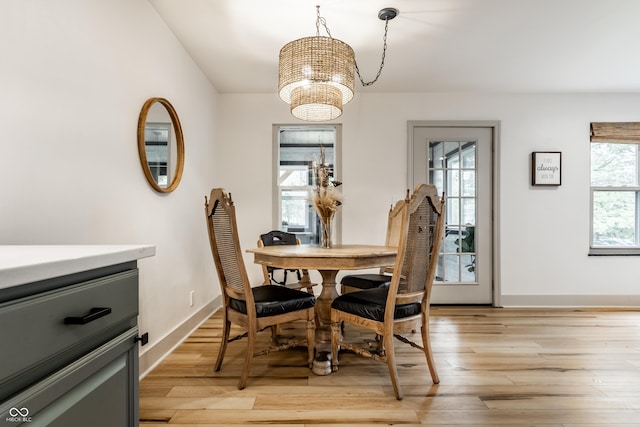 dining area featuring a chandelier, light wood finished floors, and baseboards