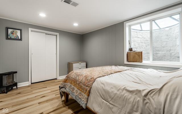 bedroom featuring light wood-style flooring, ornamental molding, multiple windows, recessed lighting, and a closet