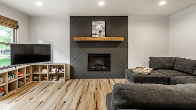 living room with wood finished floors, recessed lighting, and a fireplace