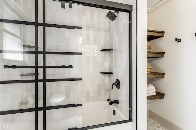 bathroom featuring combined bath / shower with glass door and baseboards