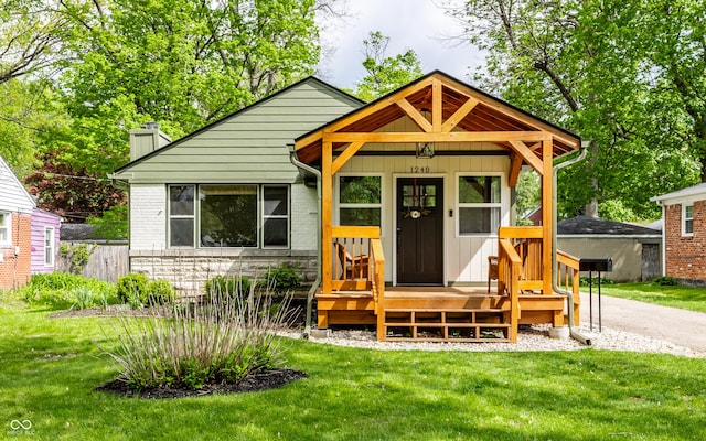 bungalow with a chimney, stone siding, and a front lawn