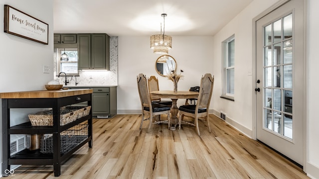 dining space featuring a chandelier, light wood finished floors, and baseboards