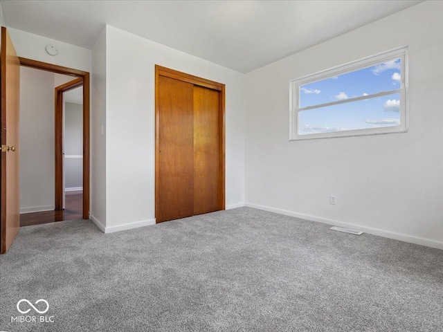 unfurnished bedroom with carpet flooring, baseboards, and a closet
