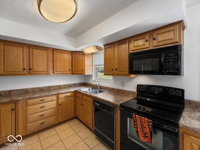 kitchen featuring black appliances, a sink, brown cabinetry, a textured ceiling, and dark countertops