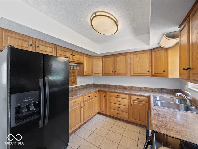 kitchen featuring black appliances, a sink, a textured ceiling, light tile patterned floors, and a tray ceiling