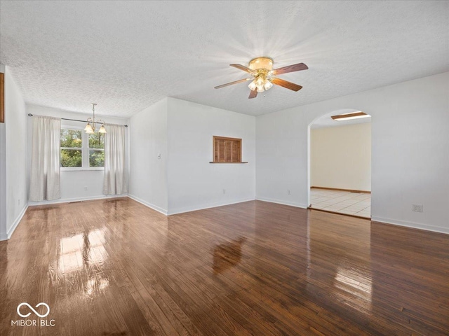 unfurnished living room with arched walkways, wood finished floors, a textured ceiling, ceiling fan, and a chandelier