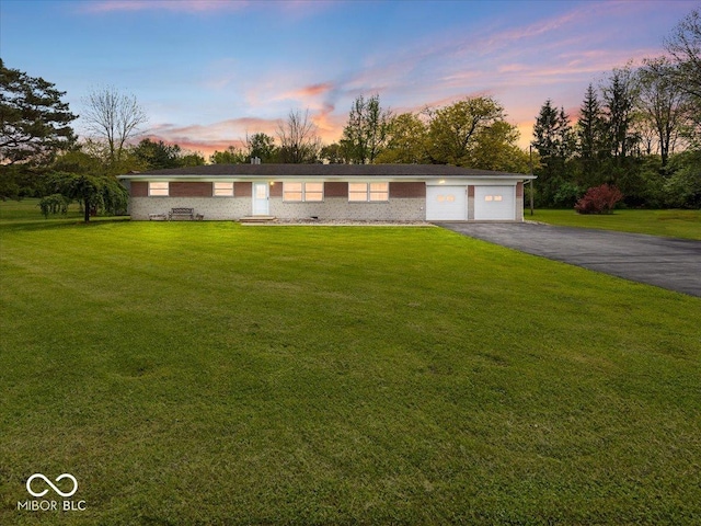 ranch-style home featuring asphalt driveway, a lawn, and brick siding