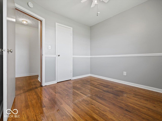 empty room with a ceiling fan, wood finished floors, baseboards, and a smoke detector