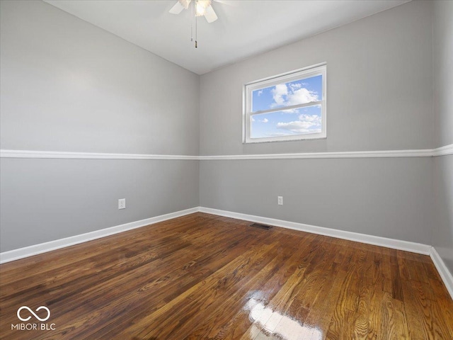 spare room with baseboards, a ceiling fan, and dark wood-style flooring