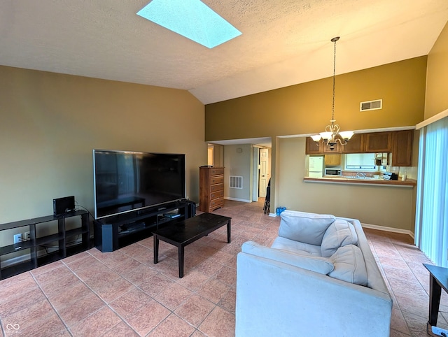 living room featuring a chandelier, lofted ceiling, a skylight, a textured ceiling, and baseboards