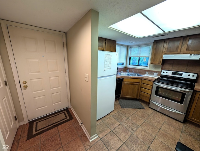 kitchen featuring electric stove, freestanding refrigerator, ventilation hood, dishwasher, and a sink