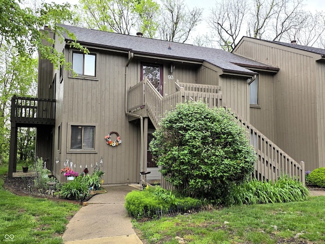 view of front of house featuring a balcony, roof with shingles, and stairs