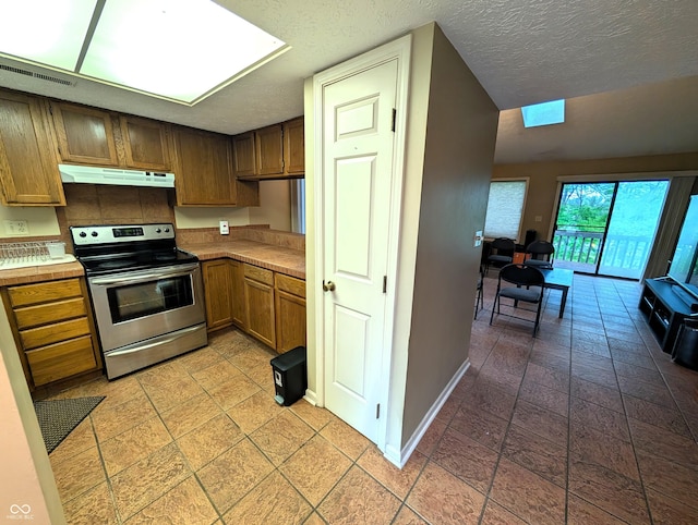 kitchen with stainless steel electric range, under cabinet range hood, baseboards, light countertops, and a textured ceiling