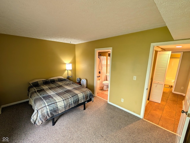 bedroom with a textured ceiling, carpet floors, baseboards, and ensuite bathroom