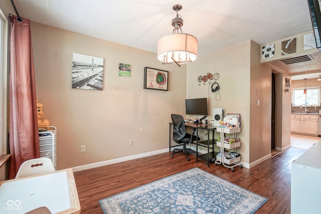 office area featuring wood finished floors, baseboards, and a sink