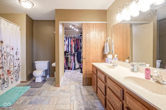 full bathroom with toilet, stone finish flooring, double vanity, baseboards, and a shower with curtain