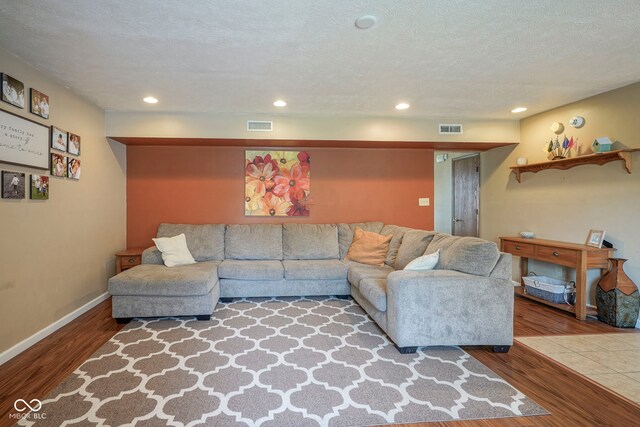 living room with wood finished floors, baseboards, recessed lighting, and a textured ceiling