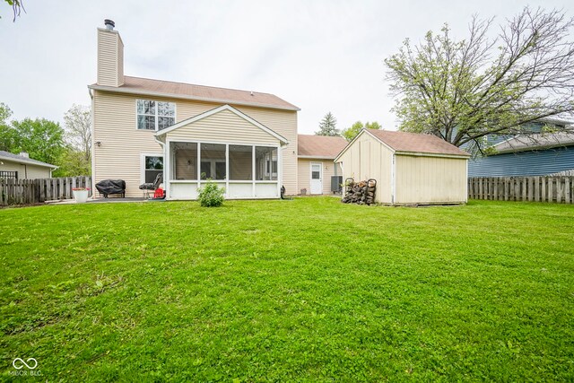 rear view of house featuring a sunroom, a storage shed, an outbuilding, a chimney, and a patio