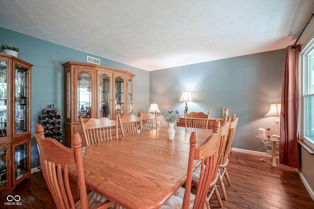 dining space featuring wood finished floors, baseboards, and a textured ceiling