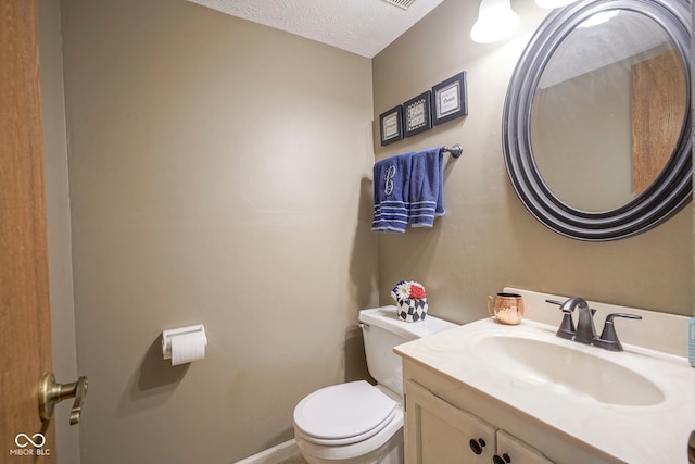 bathroom with toilet, vanity, a textured ceiling, and baseboards
