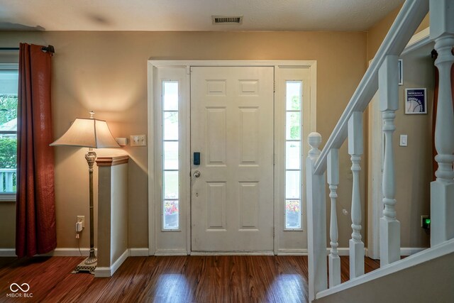 entryway with stairway, wood finished floors, and plenty of natural light